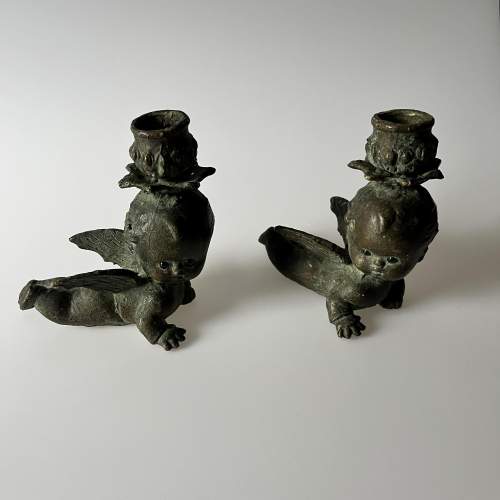 A Pair of Bronze Cherub Candlesticks with Green Glass Eyes image-1